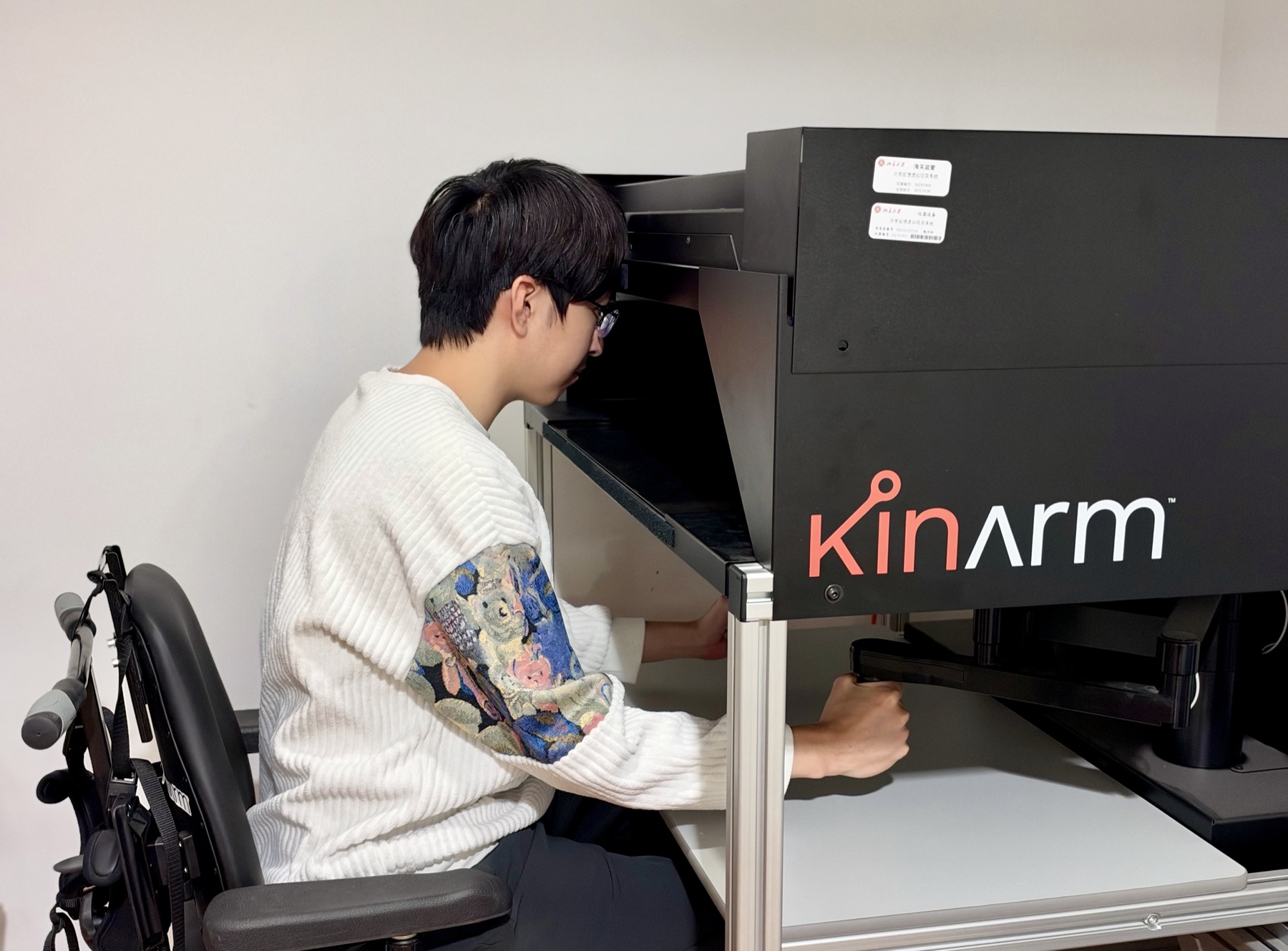 A participant holding the handles of a KINARM robot in the laboratory.
